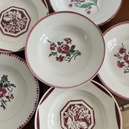 Composition d'assiettes creuses en faïence ancienne dans les tons rouges (lunéville, badonviller, digoin)